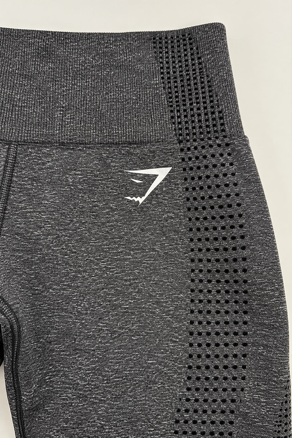 Close-up of white Gymshark logo and seamless knit pattern on grey leggings